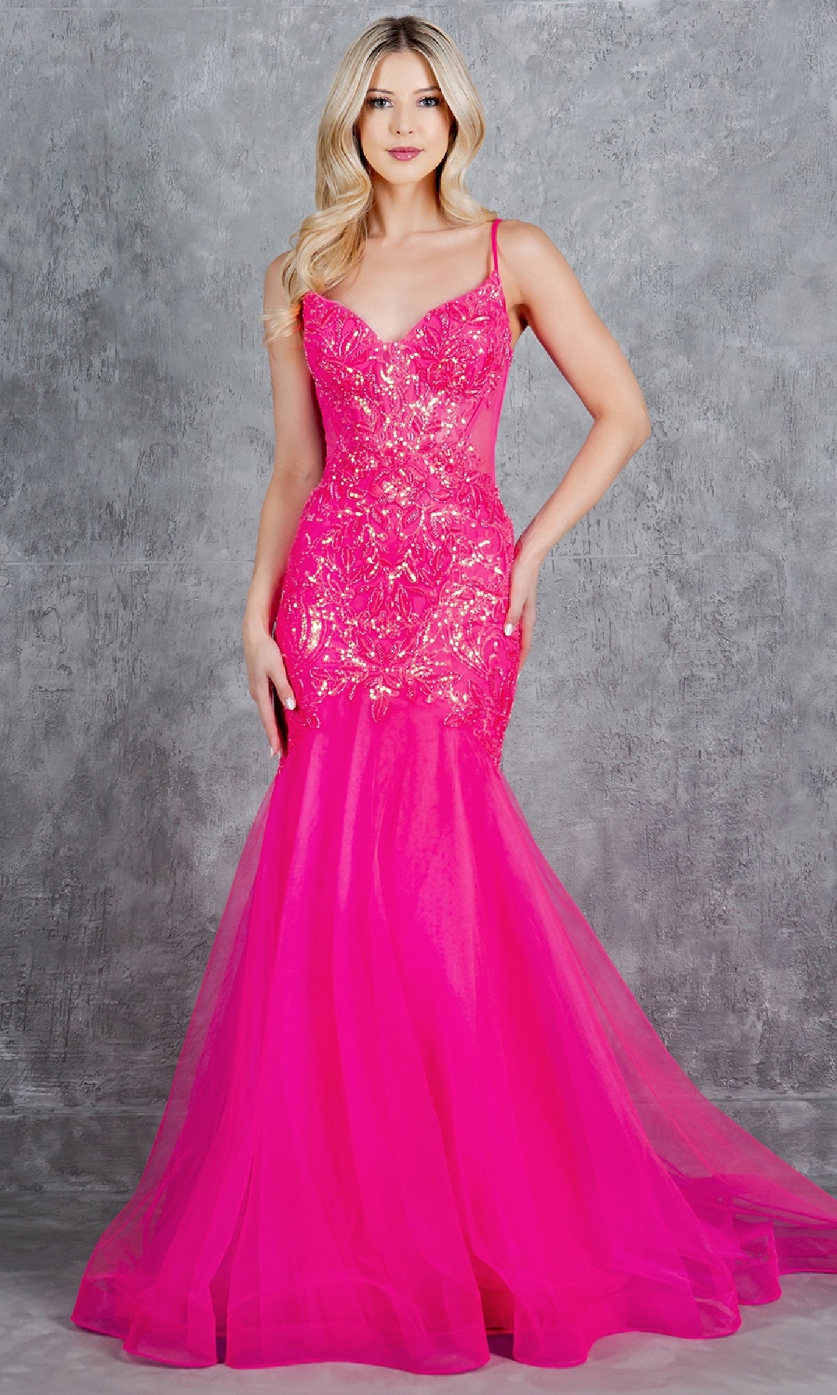 A woman in the Long Mermaid Prom Dress: Cinderella Couture 8276J—a bright pink sequin evening gown—stands against a gray textured background.